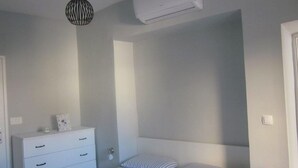 Un dormitorio con cama, mesita de noche y lámpara colgante.