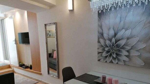 Una sala de estar moderna con comedor, una obra de arte floral grande en la pared y un televisor de pantalla plana sobre el sofá.