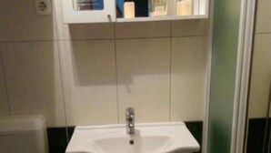 Un baño con lavamanos blanco, inodoro y zona de ducha.