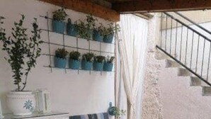 Una habitación con una mesa blanca y bancos, una escalera y un estante para plantas en la pared.