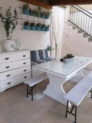 Ein Zimmer mit weißem Tisch, Bänken, einer Treppe und einem an der Wand befestigten Pflanzenregal.