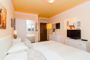 Ein Hotelzimmer mit Bett, Fernseher, Kommode und einer Tür zu einem weiteren Raum.