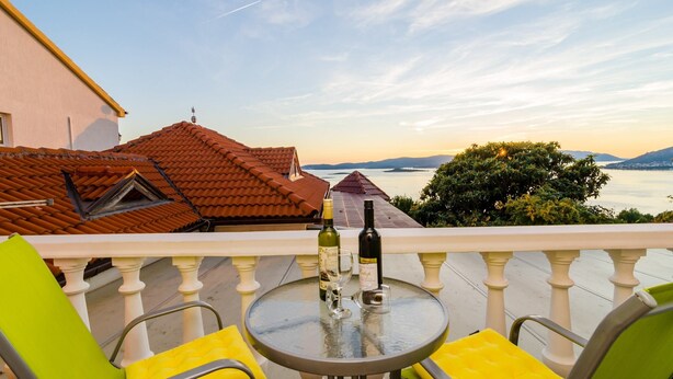 Un balcone con tavolo, sedie e una bottiglia di vino.