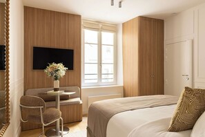 Ein Hotelzimmer mit einem Bett, einer Sitzecke mit einem Sessel, einem Fernseher und einem Kleiderschrank.
