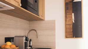 A modern kitchen with wooden cabinets, a Bosch microwave, a coffee machine, and a sink. - Sublime Suite Saint Honore, Elysee Palace (Paris)