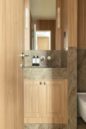 Ein modernes Badezimmer mit Holzschränken, einer Marmorplatte und einem Spiegel.