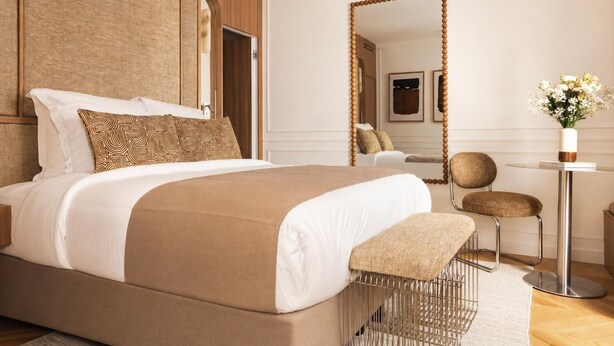 A modern bedroom with a large bed, a side table, a chair, and a mirror. - Sublime Suite Saint Honore, Elysee Palace (Paris)