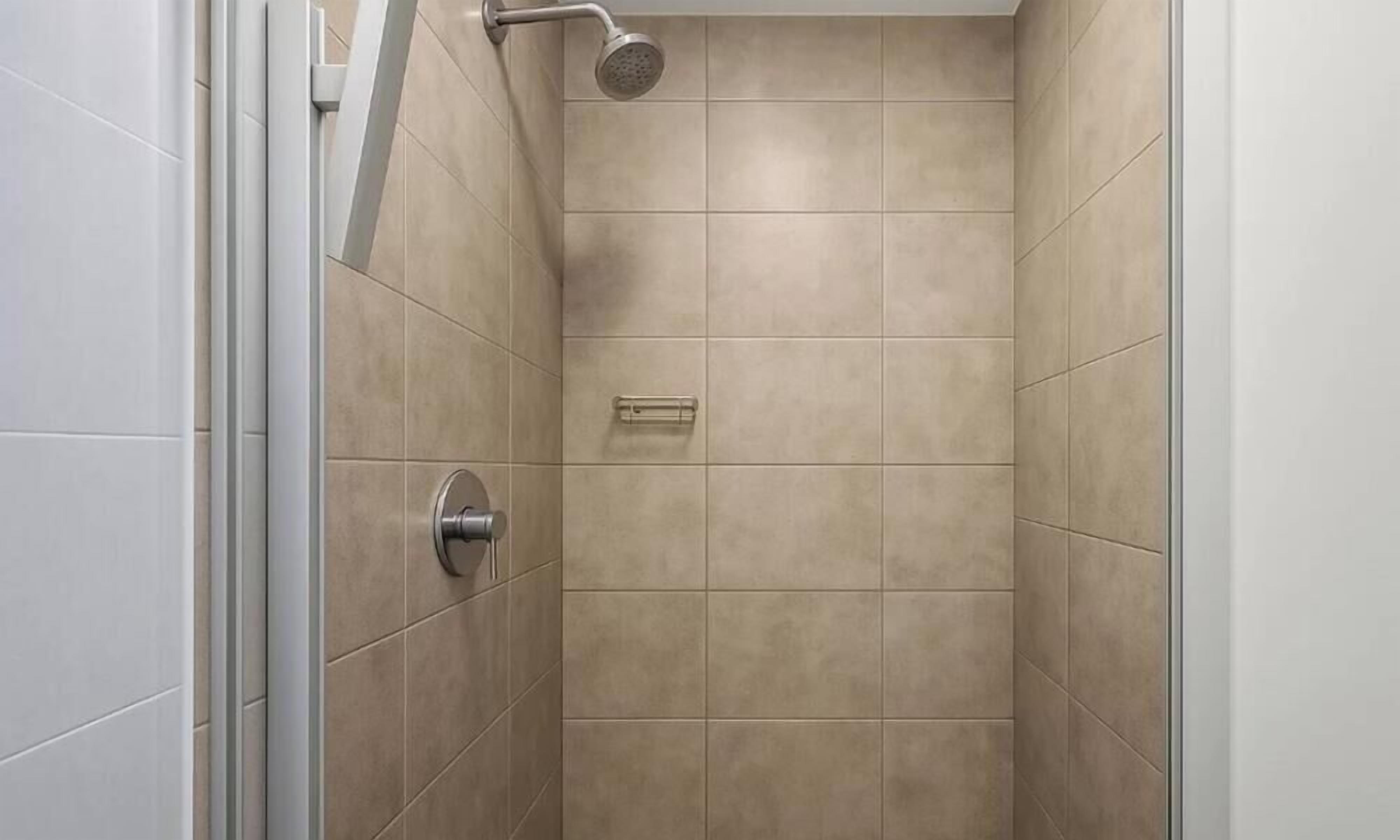 Ducha con azulejos color crema, cabezal de ducha de mano y panel de control.