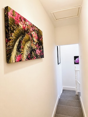 A hallway with a staircase, a wall-mounted painting, and a door at the end. - Cosy room in Wolverhampton perfect for contractors (Wolverhampton)