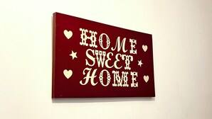 A rectangular sign with the phrase 'HOME SWEET HOME' in white letters on a red background, surrounded by white stars and hearts. - Cosy room in Wolverhampton perfect for contractors (Wolverhampton)