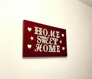 A rectangular sign with the phrase 'HOME SWEET HOME' in white letters on a red background, surrounded by white stars and hearts. - Cosy room in Wolverhampton perfect for contractors (Wolverhampton)