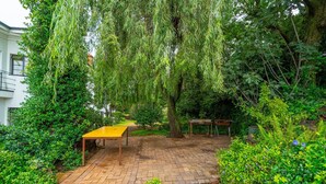 A brick patio with a yellow table and chairs, surrounded by lush greenery and trees. - Double Self-Contained Room (Johannesburg)