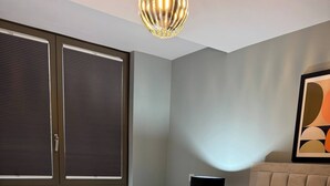 A hotel room with a bed, a nightstand, a lamp, and a window with blinds. - Apartment in Botanical Gardens, Old Trafford (Stretford, old Trafford)