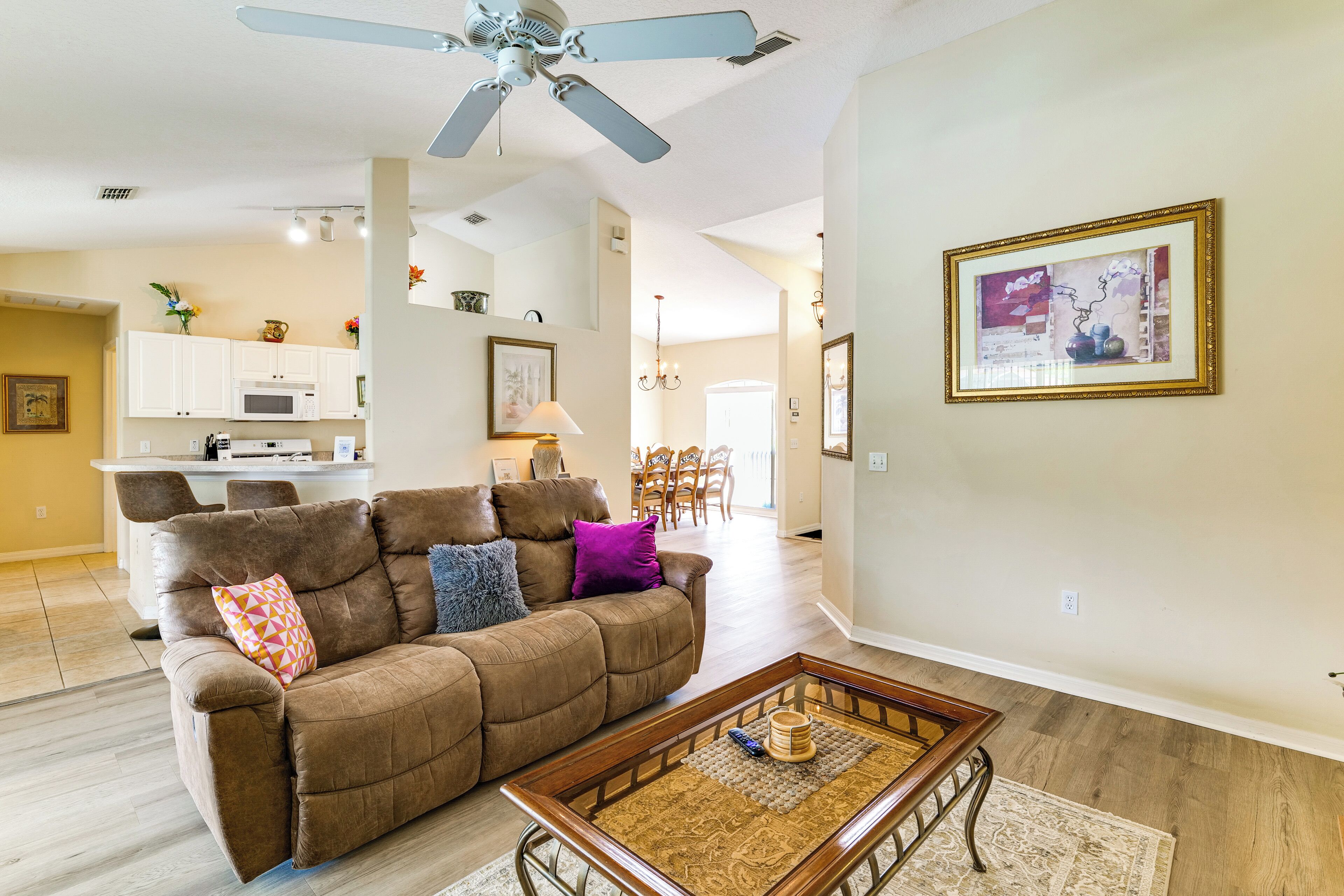 A living room with a brown sofa, a coffee table, and a ceiling fan.