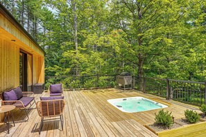 A wooden deck with a hot tub, outdoor furniture, and a barbecue grill.
