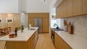 Una cocina moderna con armarios de madera, un refrigerador de acero inoxidable y una encimera de mármol.