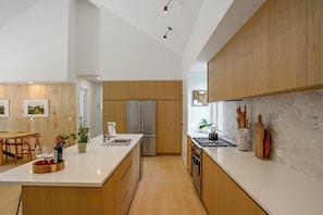 Eine moderne Küche mit Holzschränken, einem Edelstahlkühlschrank und einer Marmorarbeitsplatte.