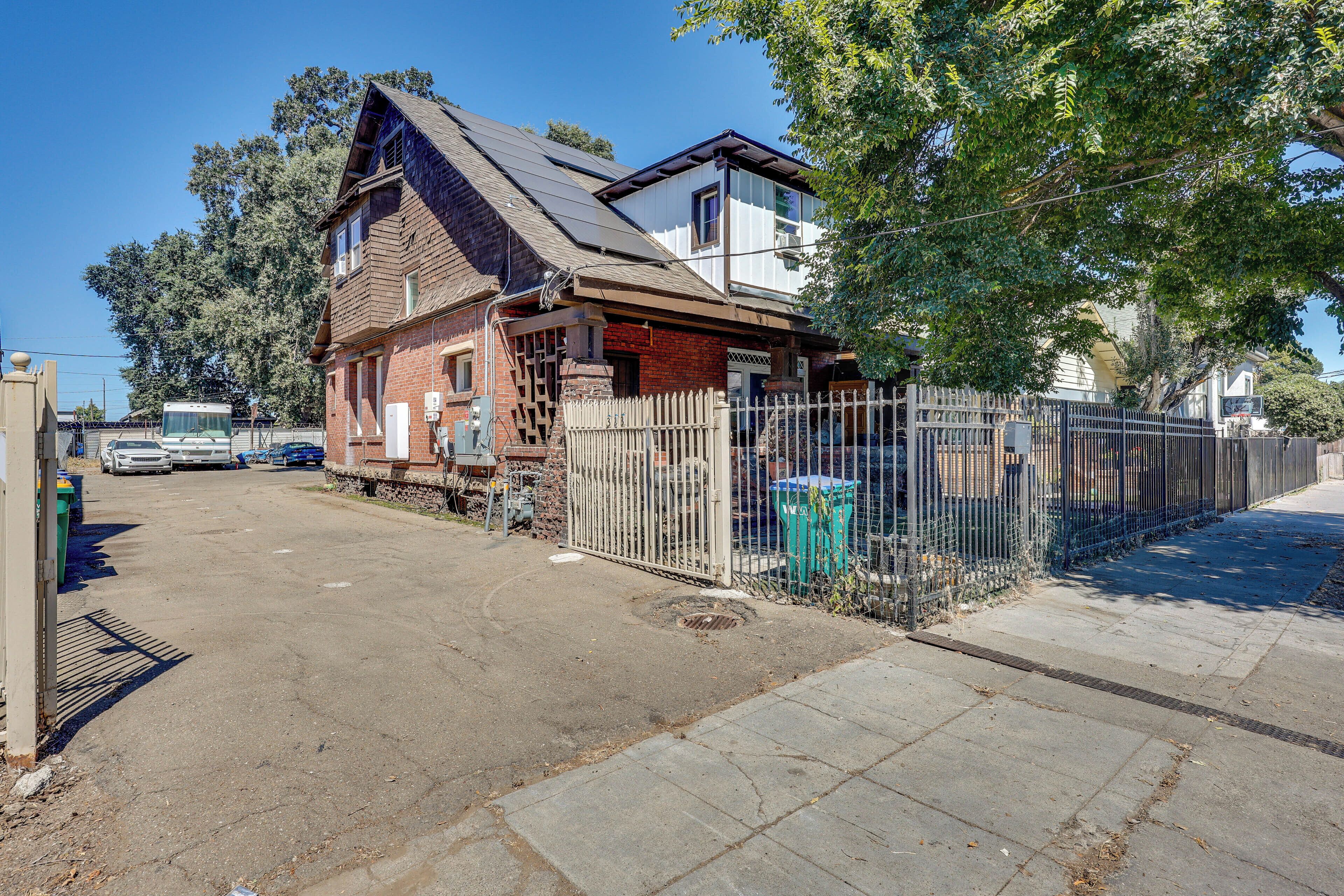 A two-story building with a brick facade and a metal fence.