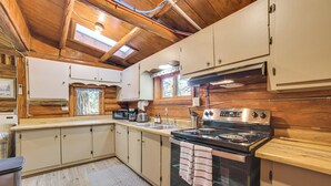 Cocina compacta con gabinetes de madera, estufa y microondas.