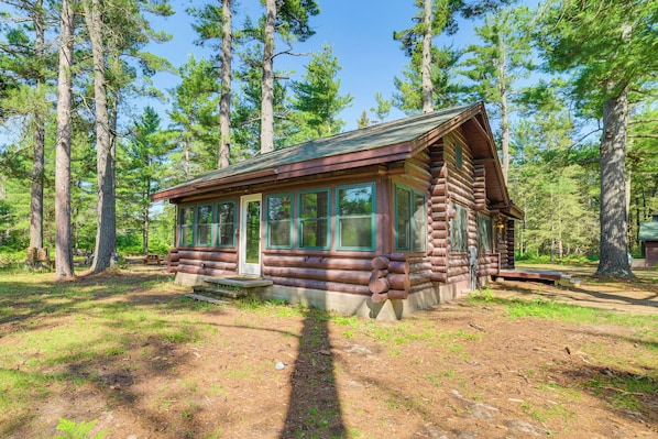 Eine Blockhütte mit Veranda, umgeben von hohen Bäumen.