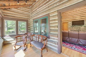 Ein Holzblockhaus-Interieur mit Holzböden, einem Steinkamin und einer Sitzgruppe.