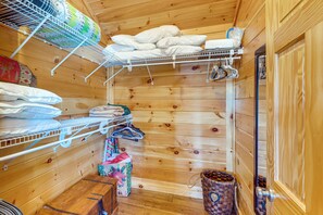 Ein Holzinnenraum mit einem Bett, Regalen und einer Kleiderstange.
