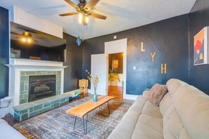 Ein Wohnzimmer mit Kamin, Deckenventilator und einer Couch.
