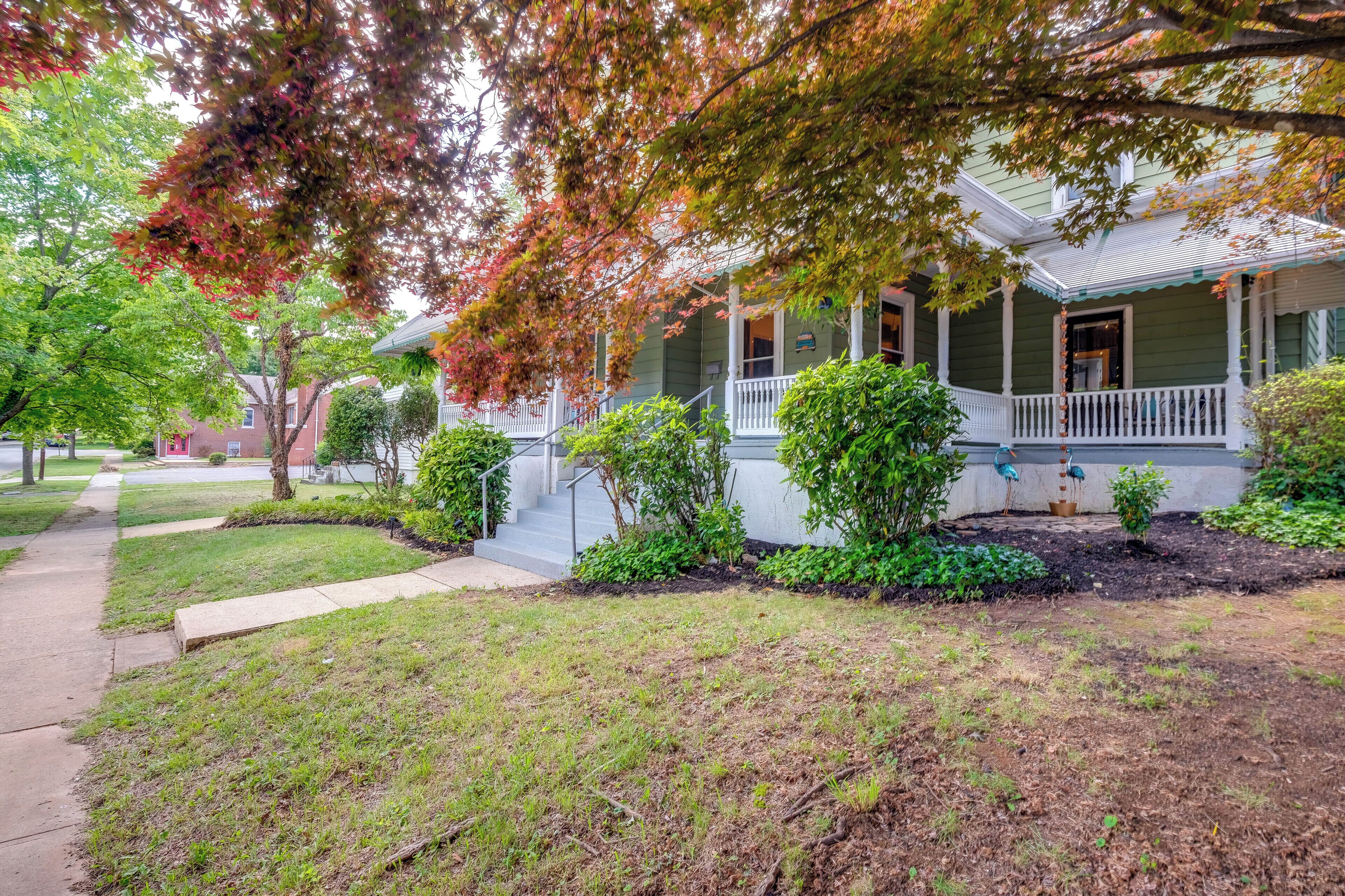 A two-story house with a front porch, a small garden, and a sidewalk leading to the entrance.