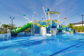 A water park with a large slide, multiple water features, and a clear blue sky. - Private Pool & Game Room! ChampionsGate Resort Gem (Davenport)