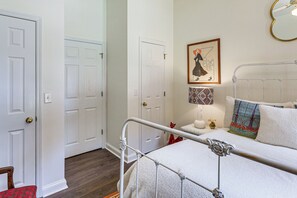Ein Schlafzimmer mit einem Metallbettgestell, weißen Wänden und einer Tür mit Messingknauf.
