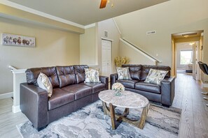 A living room with two dark brown leather sofas, a round coffee table, and a patterned rug. - Pool Access & Balcony! Colorado Springs Getaway (Colorado Springs)