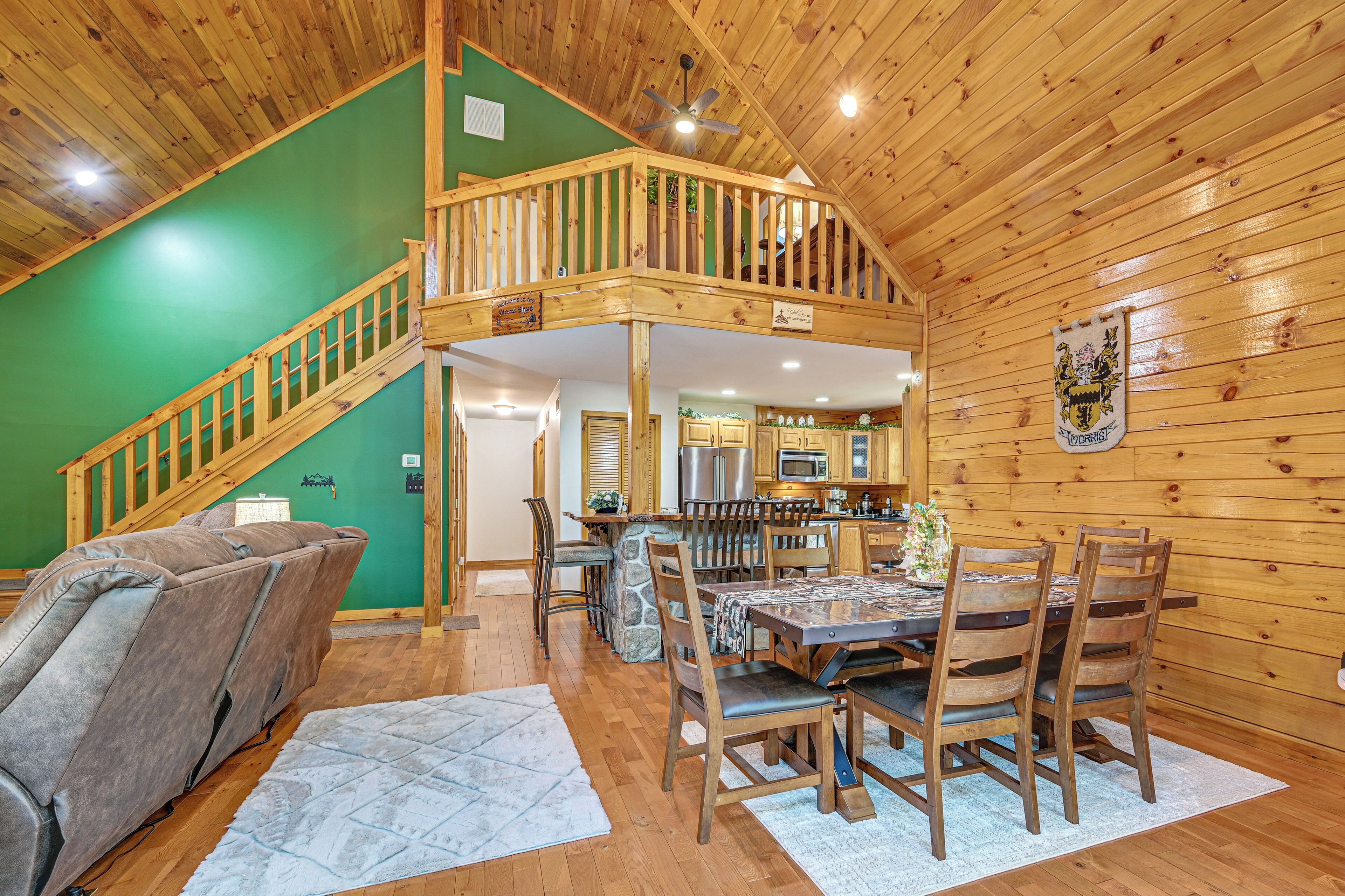 A wooden interior with a dining area, kitchen, and a staircase leading to an upper level.