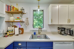 A kitchen with white cabinets, a Bosch dishwasher, a coffee maker, and a window with a view of trees. - Family-Friendly Poconos Getaway 11 Mi to Kalahari! (Cresco)