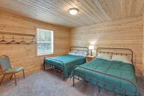 Ein Zimmer mit zwei Betten, einem Sessel, einem Fenster und einer Lampe.