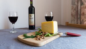 Puinen leikkuulauta, jonka päällä on juustosiivu, pullo Merlot-viiniä ja kaksi viinilasia pöydällä.