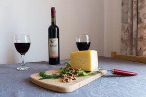 Ein Holztisch mit einem Käsekeil, einer Merlot-Flasche und zwei Weingläsern.