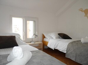 A hotel room with two beds, a window, and a desk with a lamp. - Dugi Rat Seaside Apartments - 2 Bedroom 6 (Dugi Rat)