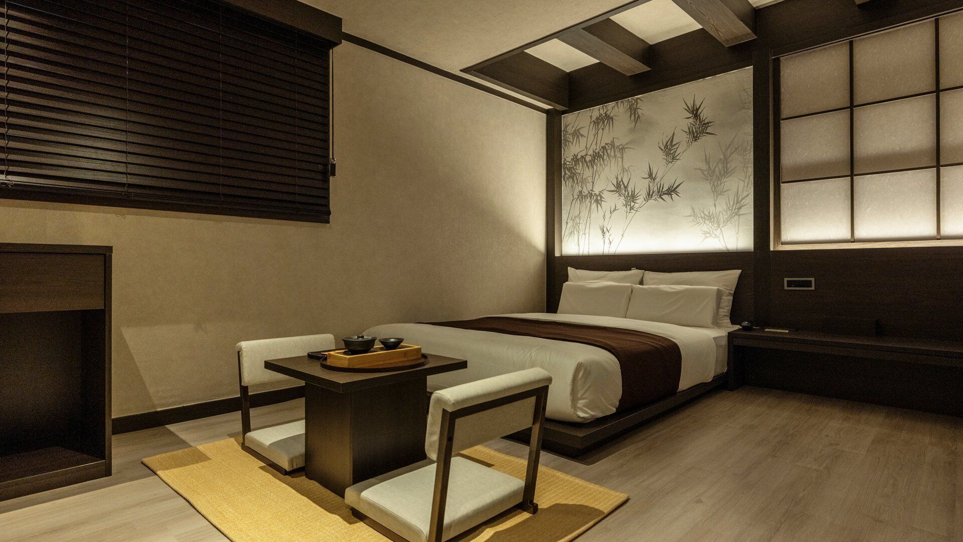 A modern bedroom with a bed, bedside table, and a view of bamboo through a window.