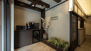 A reception area with a coffee machine, a potted plant, and a sign for the Koharu Ryokan Hotel. - Koharu Ryokan Hotel Suwon Ingye (Suwon)