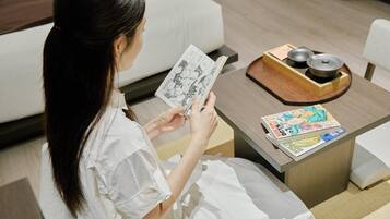 Una persona leyendo manga sobre una mesita con un cuenco y palillos a su lado.