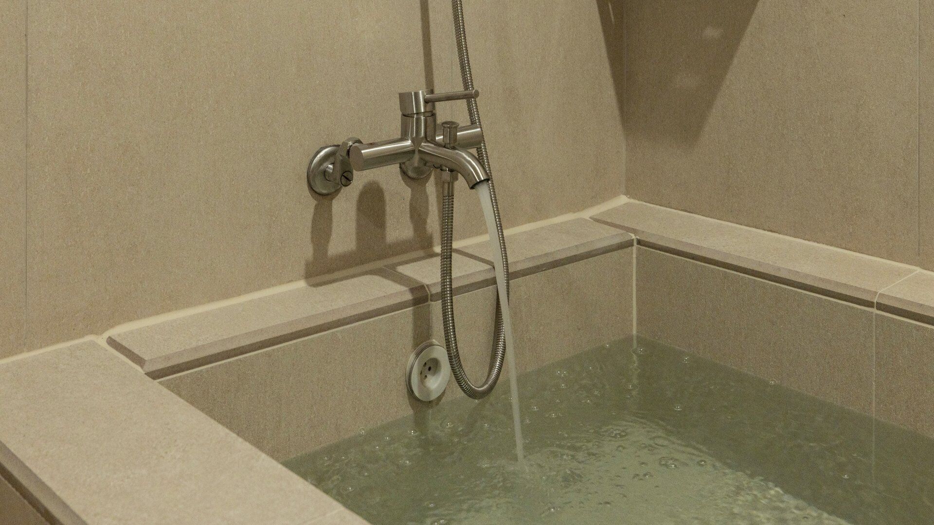Eine Dusche mit Handbrause und Wandarmatur.