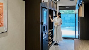 A self-service card machine with a digital display, a person interacting with it, and a view of the outdoors through a glass door. - Koharu Ryokan Hotel Suwon Ingye (Suwon)