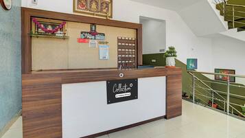 A reception desk with a sign indicating it's a company-serviced location, a clock, and a staircase in the background.