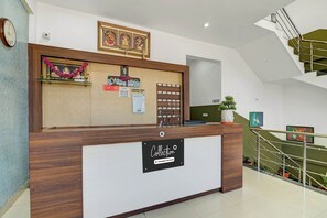 Un mostrador de recepción con un cartel que indica que es un lugar de servicio de empresa, un reloj y una escalera al fondo.