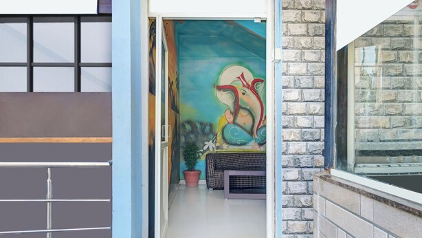 A doorway leading to a room with a mural, a potted plant, and a patterned bench. - Super Collection O by OYO Nayagaon Vikas (Chikkamagaluru)