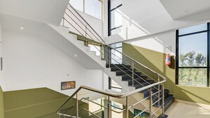 A modern interior with a staircase, glass railings, and a fire extinguisher. - Super Collection O by OYO Nayagaon Vikas (Chikkamagaluru)