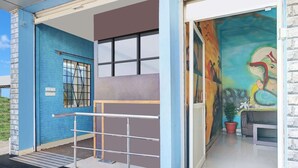 A building entrance with a blue exterior, a metal gate, and a mural on the wall.