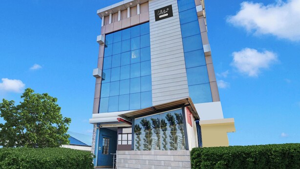 A modern building with a glass facade, a sign indicating a company service, and a clear blue sky.