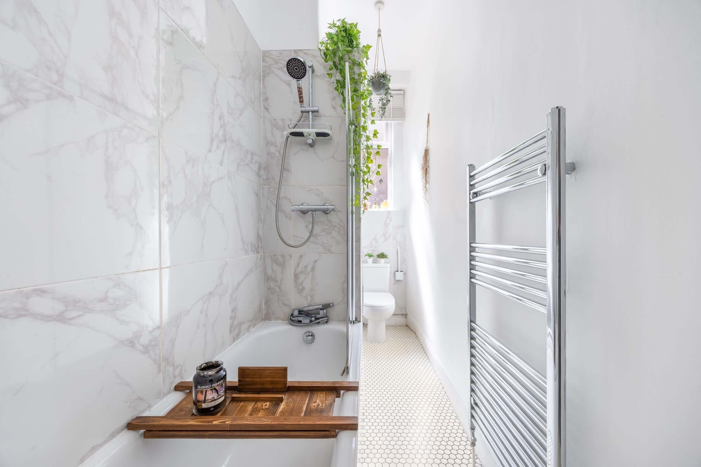 A bathroom with a shower, toilet, and a wooden shelf with a jar.