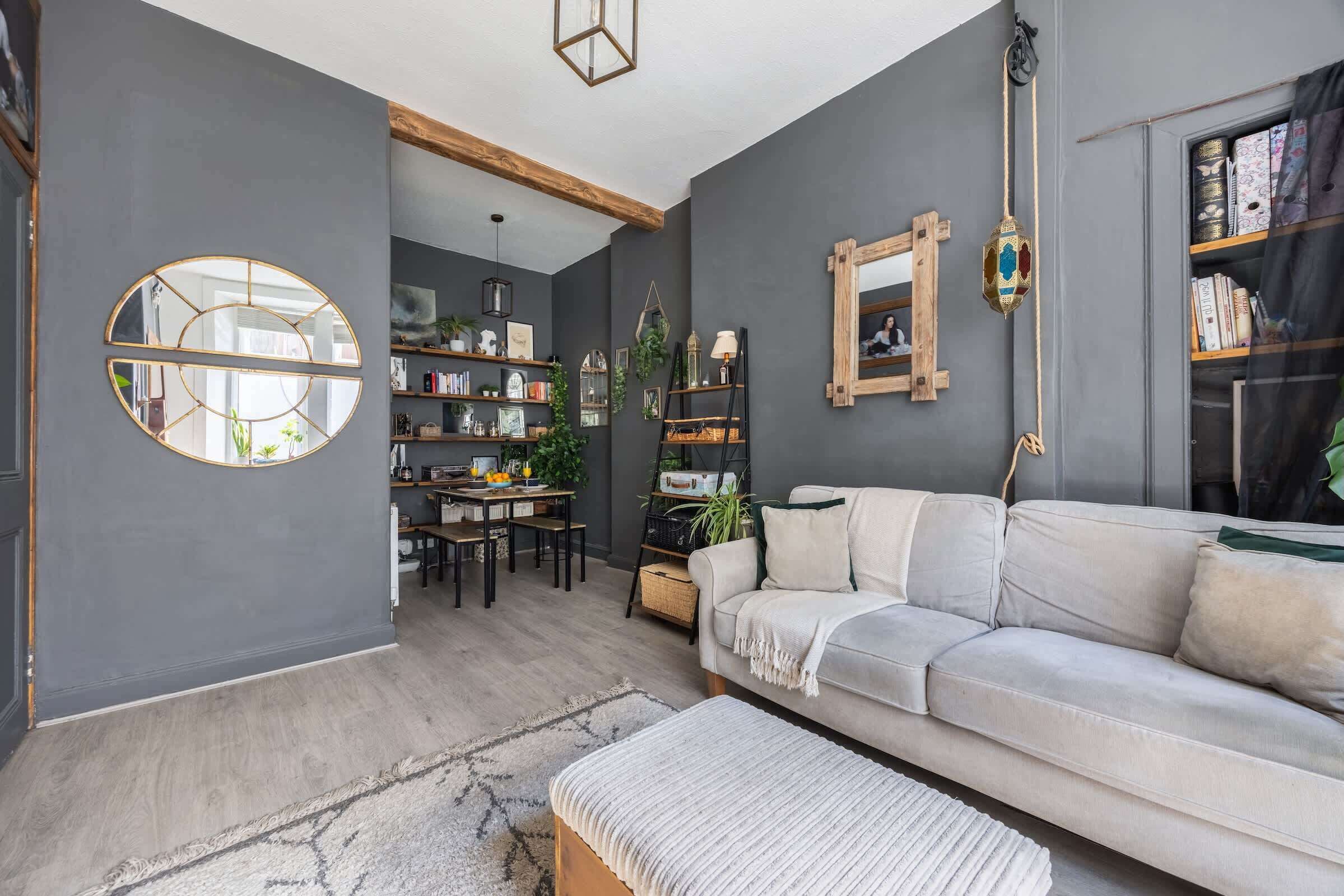 Una sala de estar moderna con un sofá gris, una mesa de comedor y una estantería.